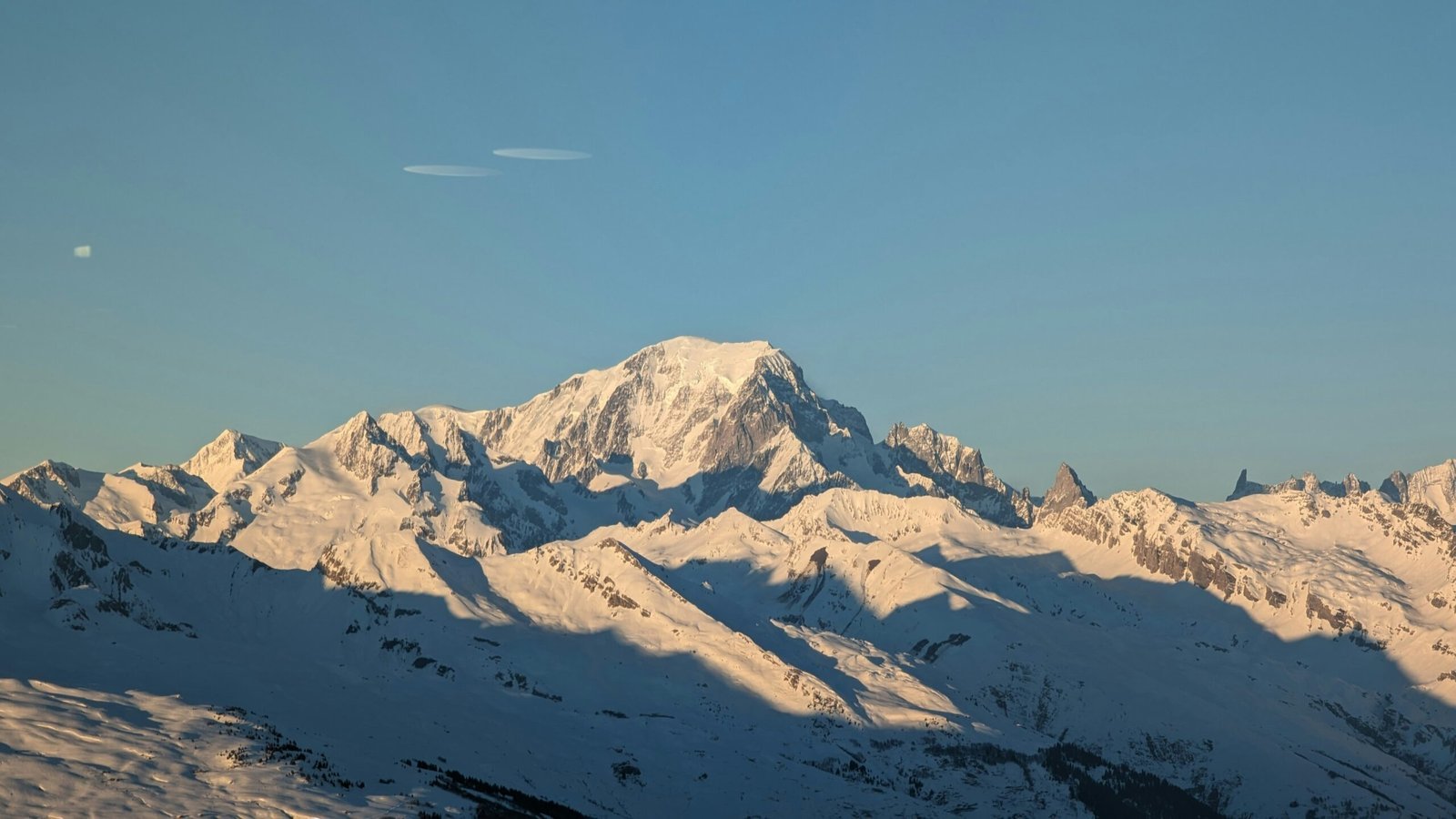A view of a snowy mountain range at sunset